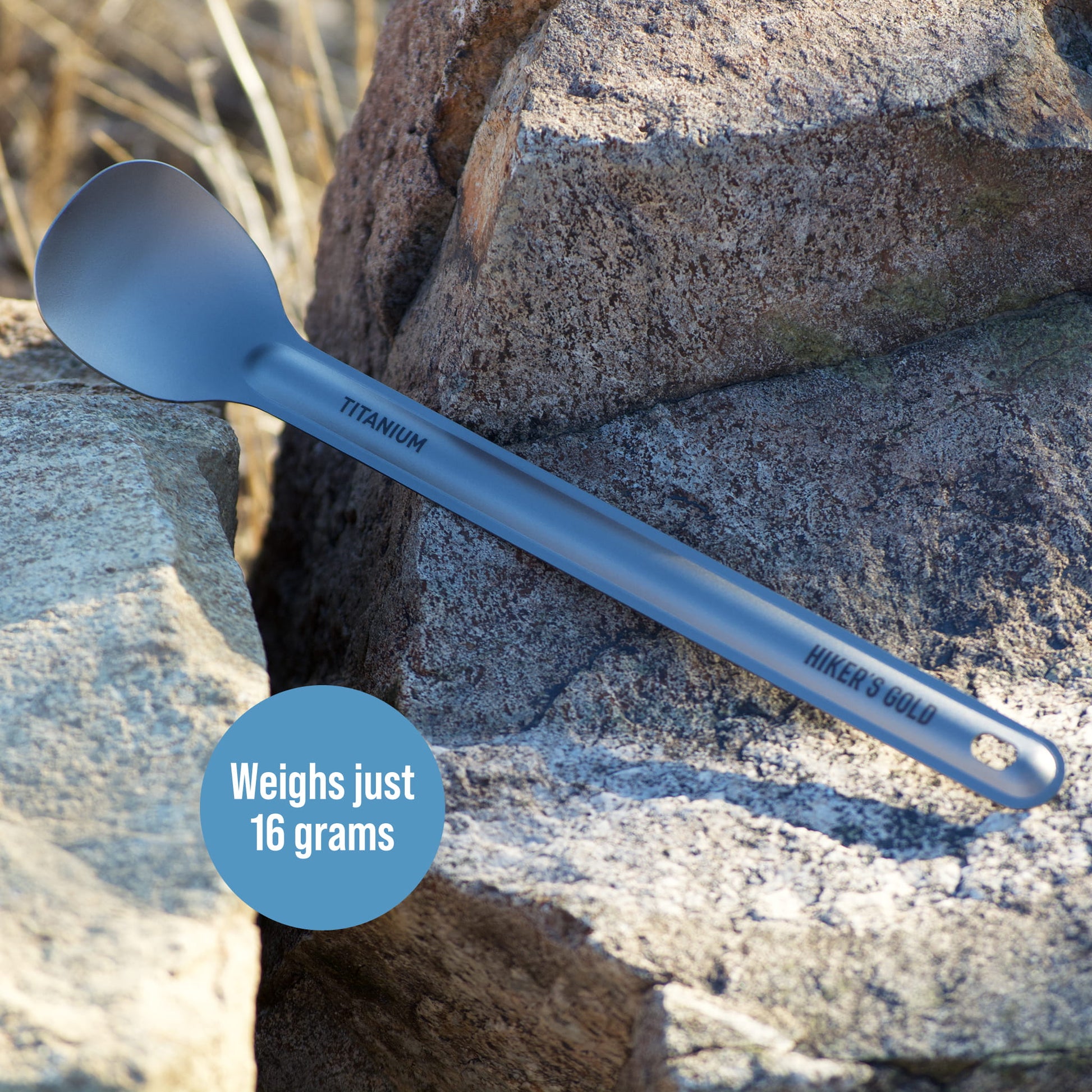 Blue titanium spoon on a rock with 'Hiker's Gold' branding