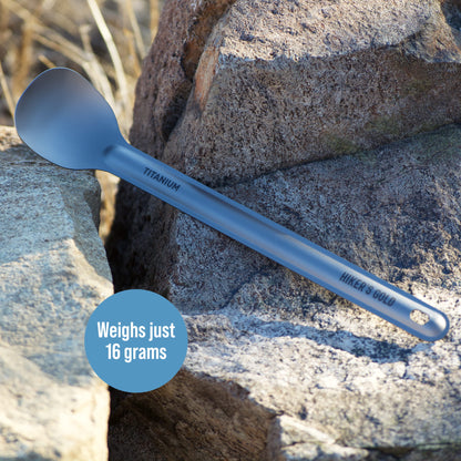 Blue titanium spoon on a rock with 'Hiker's Gold' branding